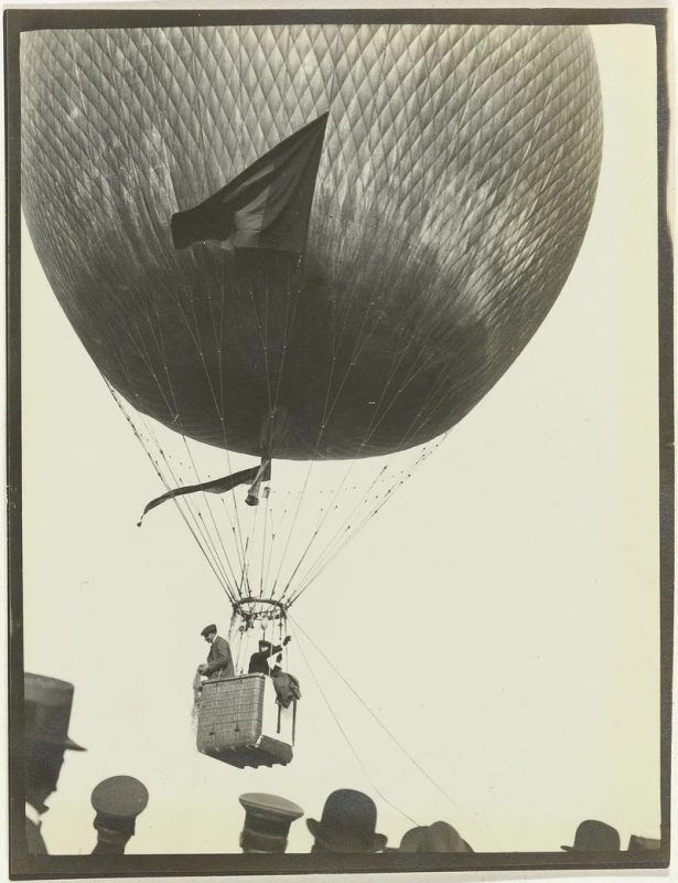 Black and white photo of a hot air balloon with 2 passengers in it.