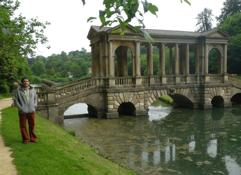 A lake with lush grasses along the banks and a bridge built across it.