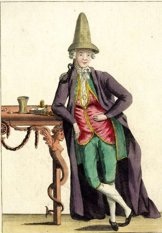 An image of a man dressed in macaroni fashion—long black coat on top of a red suit and a green knee pants, plus a tall pointed hat.
