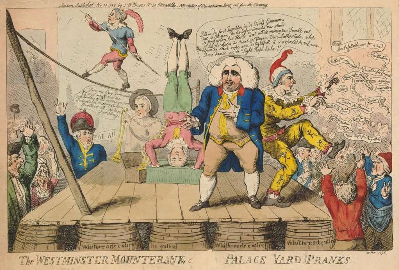 Men on stage performing circus antics in front of a crowd.