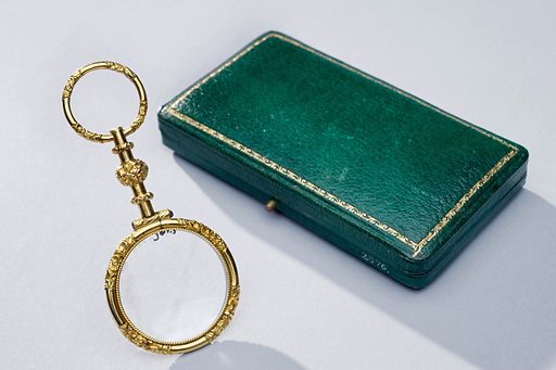 A picture of a quizzing glass beside a green box.